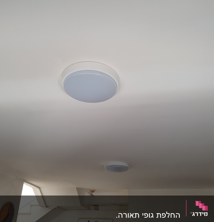 שני גופי תאורה עגולים מותקנים בתקרה לבנה